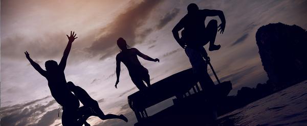 silhouette of travellers leaping off a dock